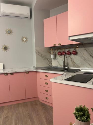 a pink kitchen with white cabinets and a sink at Central Gem Tirana in Tirana