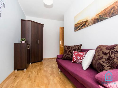 a living room with a purple couch and a cabinet at Soft Room in Gdańsk