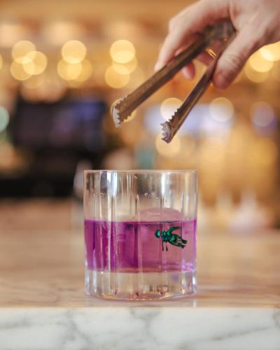 a person holding a stick in a glass with a beetle on it at Virgin Hotels New Orleans in New Orleans