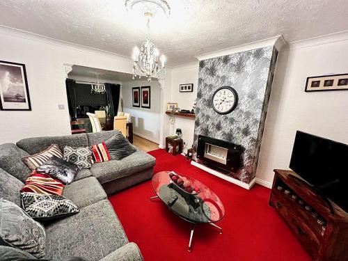 a living room with a couch and a clock on the wall at 50 Etherley Lane in Bishop Auckland