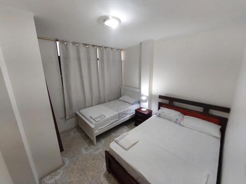 Habitación pequeña con 2 camas y ventana en Departamentos de la Costa3, en Machala