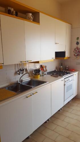 a kitchen with white cabinets and a sink at Casa delle Pomelie - Taormina & Etna Panoramic Views in Riposto