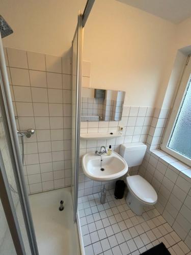 La salle de bains est pourvue de toilettes, d'un lavabo et d'une douche. dans l'établissement JonnysHostel, à Osnabrück