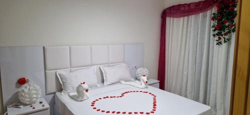 Un dormitorio con una cama blanca con un corazón. en SUITES-HOME, CIDADELA, en Praia