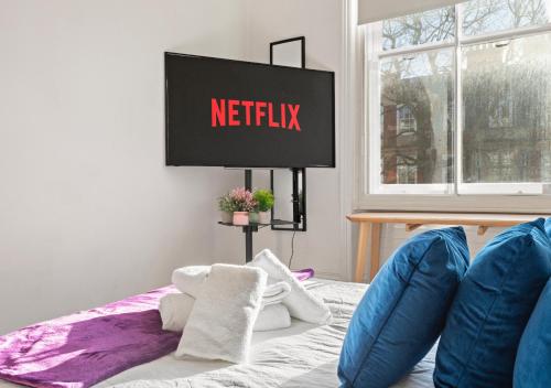 ein Schlafzimmer mit einem Bett mit einem Netflix-Schild an der Wand in der Unterkunft Classic Knightsbridge Loft Apartment in London