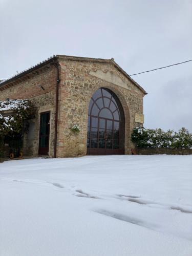 un edificio de ladrillo con una puerta en la nieve en Agriturismo Portoreschi en Saragano