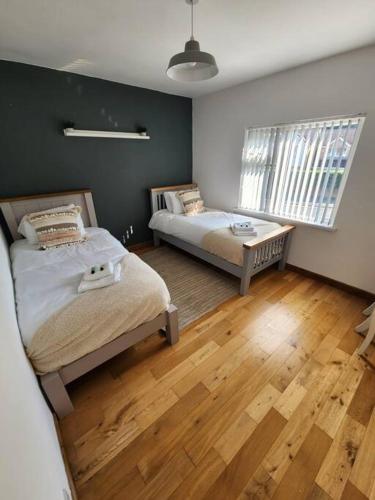 1 dormitorio con 2 camas y suelo de madera en Risca Inspire, en Risca