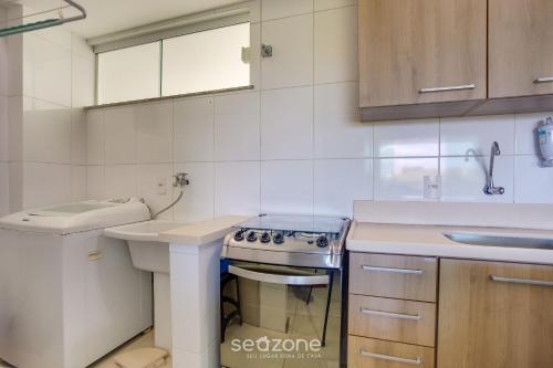 a white kitchen with a stove and a sink at Belo Apto Baia do Pontal BCL402 in Ilhéus