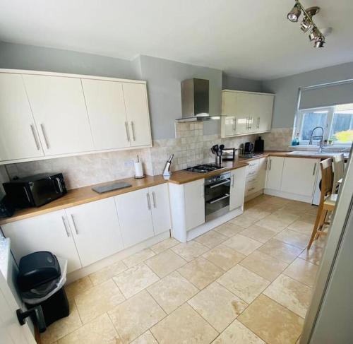 a kitchen with white cabinets and a tile floor at Risca Inspire in Risca