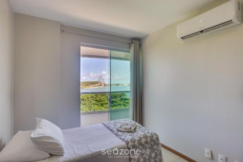a bedroom with a window with a view of the bridge at Belo Apto Baia do Pontal BCL402 in Ilhéus