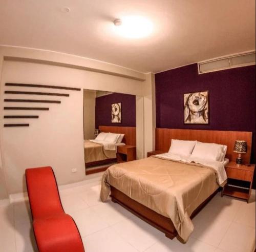 a bedroom with two beds and a red chair at Hotel Cisneros 700 in Lima