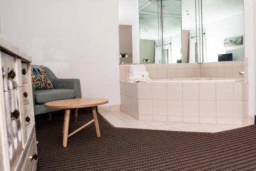 a bathroom with a tub and a table and a chair at Clock Tower Inn in Berne
