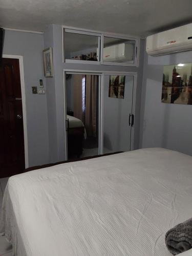 a bedroom with a white bed and a mirror at Zipcode Hideaway Guesthouse in Portmore