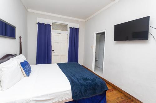 a bedroom with a bed and a flat screen tv at Caribic House in Montego Bay