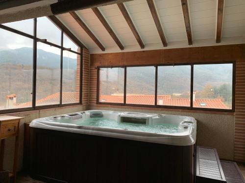 bañera grande en una habitación con ventanas en Maison de caractère avec jacuzzi entre mer et montagne à Espira de Conflent en Espira-de-Conflent
