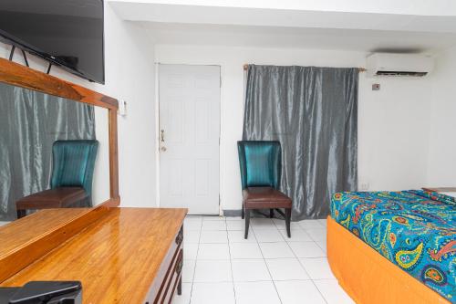 a bedroom with two chairs and a bed in it at Caribic House in Montego Bay
