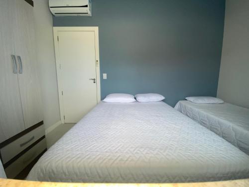twee bedden in een kleine kamer met twee witte bedden bij Residencial Belaju 02 in Bombinhas