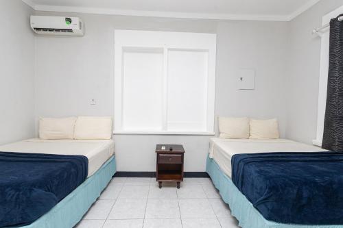 two beds in a room with a window at Caribic House in Montego Bay