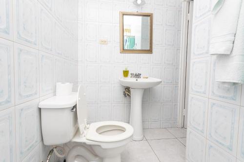 a white bathroom with a toilet and a sink at Caribic House in Montego Bay