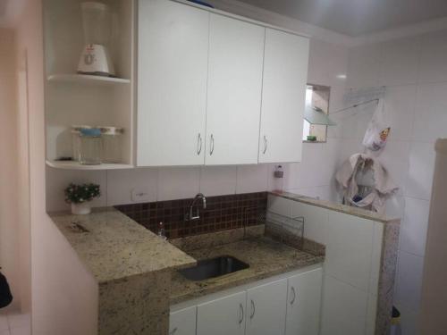 a kitchen with white cabinets and a sink at Apartamento próximo a praia in Marataizes