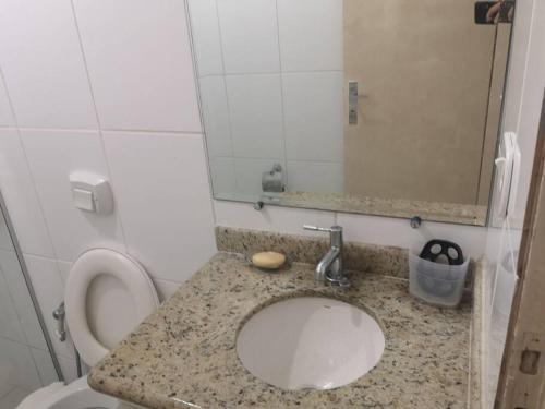 a bathroom with a sink and a toilet with a mirror at Apartamento próximo a praia in Marataizes