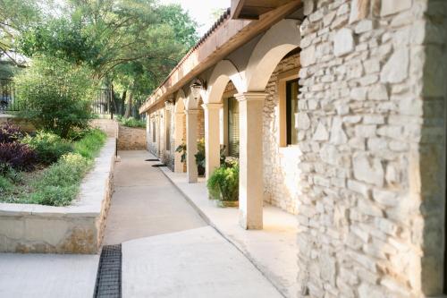 a sidewalk next to a building with a stone wall at Messina Inn in Wimberley
