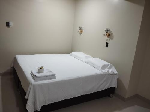 Una cama blanca con dos toallas y una vela. en Amazon deluxe, en Jaén