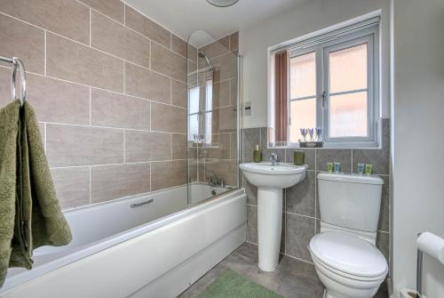 a bathroom with a toilet and a sink and a tub at Beautiful 5 Bed House Free WIFI in Coventry