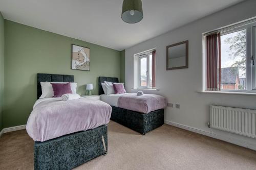 2 łóżka w pokoju z zielonymi ścianami i oknami w obiekcie Beautiful 5 Bed House Free WIFI w Coventry