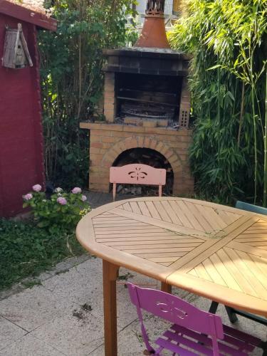 a table and two purple chairs in front of a brick oven at Chez Loti in Louviers