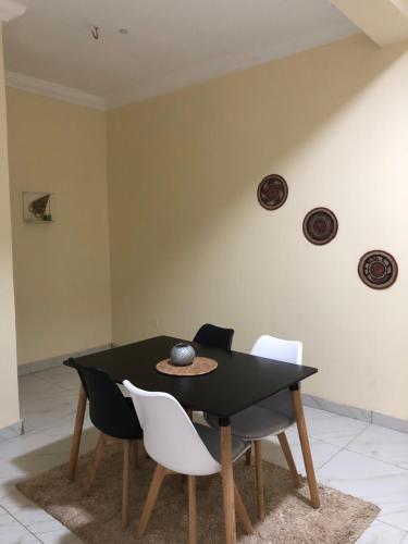 a dining room with a black table and white chairs at Furnished 2bedroom Apt in Wuye in Wupa