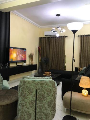 a living room with a couch and a tv at Furnished 2bedroom Apt in Wuye in Wupa