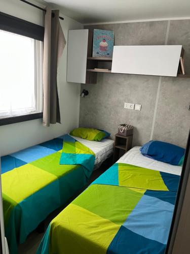 Cette chambre comprend 2 lits avec des draps colorés. dans l'établissement Mobile home Bora Bora, à Gastes