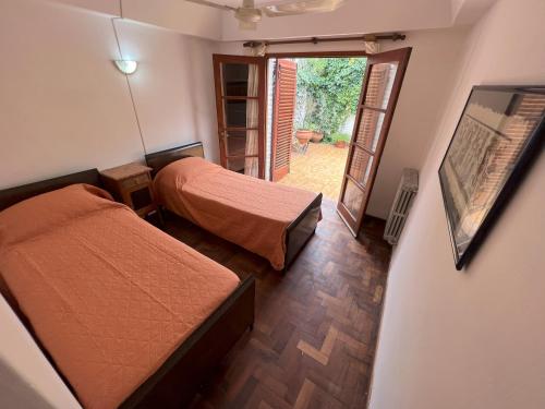 a bedroom with two beds and a door to a patio at Etels House - Departamentos Mina Clavero in Mina Clavero