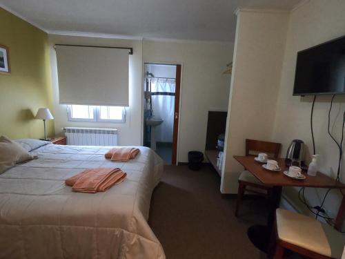 um quarto de hotel com uma cama, uma secretária e uma televisão em Los Lagos Hotel em El Calafate