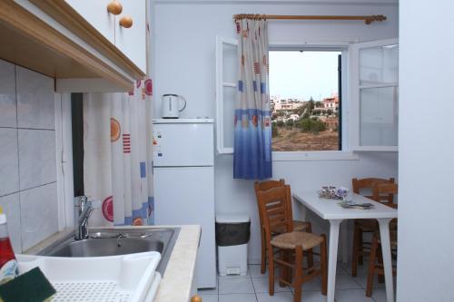 uma cozinha com um lavatório, uma mesa e uma janela em Palaiologos em Posidhonía