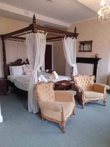 a bedroom with two beds and two chairs at The Bank House Hotel in Uttoxeter