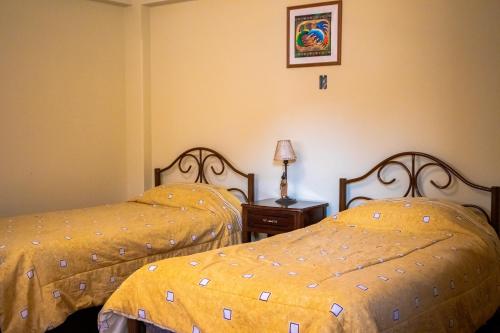 two beds in a hotel room with yellow sheets at The Hidden House Hostel in La Paz