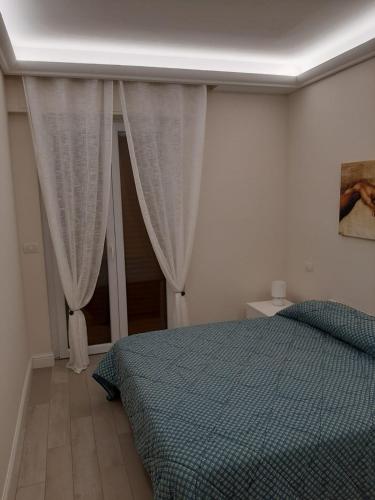 Schlafzimmer mit einem Bett mit blauer Decke und Vorhängen in der Unterkunft Cristina in Sanremo