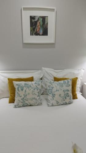 a white bed with pillows and a picture on the wall at Ferhouse Dreams Pátria in Nazaré