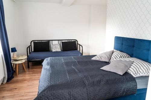 a bedroom with a blue bed and a couch at Hostel & Apartments Kołobrzeg in Kołobrzeg