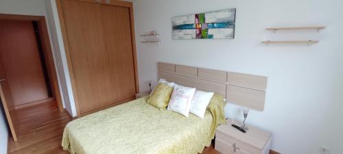 een slaapkamer met een bed met gele lakens en kussens bij EnBURELA PLAYAS DE ARENA DORADA in Burela de Cabo