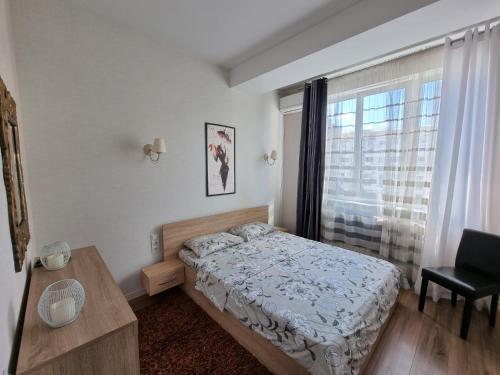 奇西瑙的住宿－Grand Central Apartment 2 bedrooms，一间卧室配有一张床、一张桌子和一个窗户。