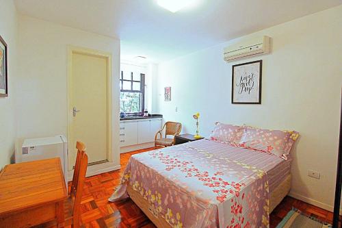 a bedroom with a bed and a table and a window at Studios do Vale 1 in Sao Paulo