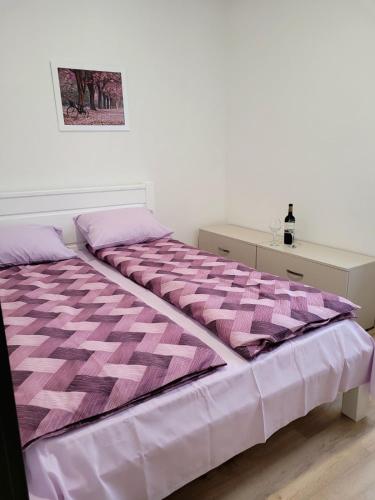 a bed with a pink comforter in a bedroom at Apartman Lukić in Banja Koviljača
