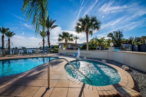 a swimming pool with palm trees and a house at Paddletail Waterfront Lodge in Crystal River