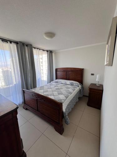 1 dormitorio con 1 cama con marco de madera en Departamento junto a la playa "Marina Horizonte", en Coquimbo