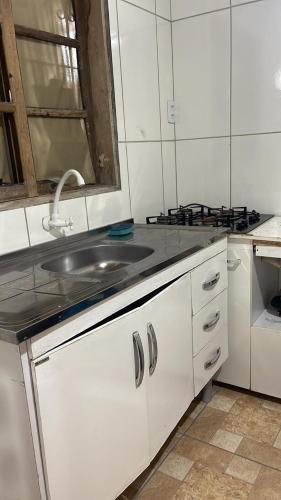 een witte keuken met een wastafel en een fornuis bij Kitnet na 262 in Itapema