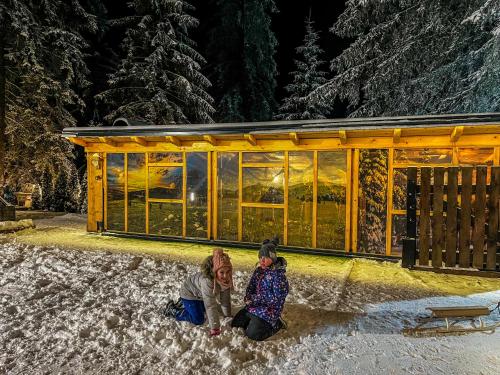 two people kneeling in the snow in front of a building at Vila Bašić Vlašić Apartman MEDO in Vlasic