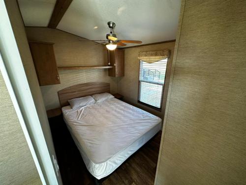 een kleine slaapkamer met een bed en een plafondventilator bij Falcon Cottages in Niagara on the Lake